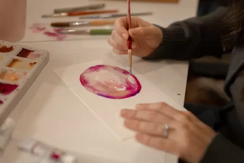 Elyse Williams Creative painting a watercolour abstract circular painting with pinks, yellows and purples in focus